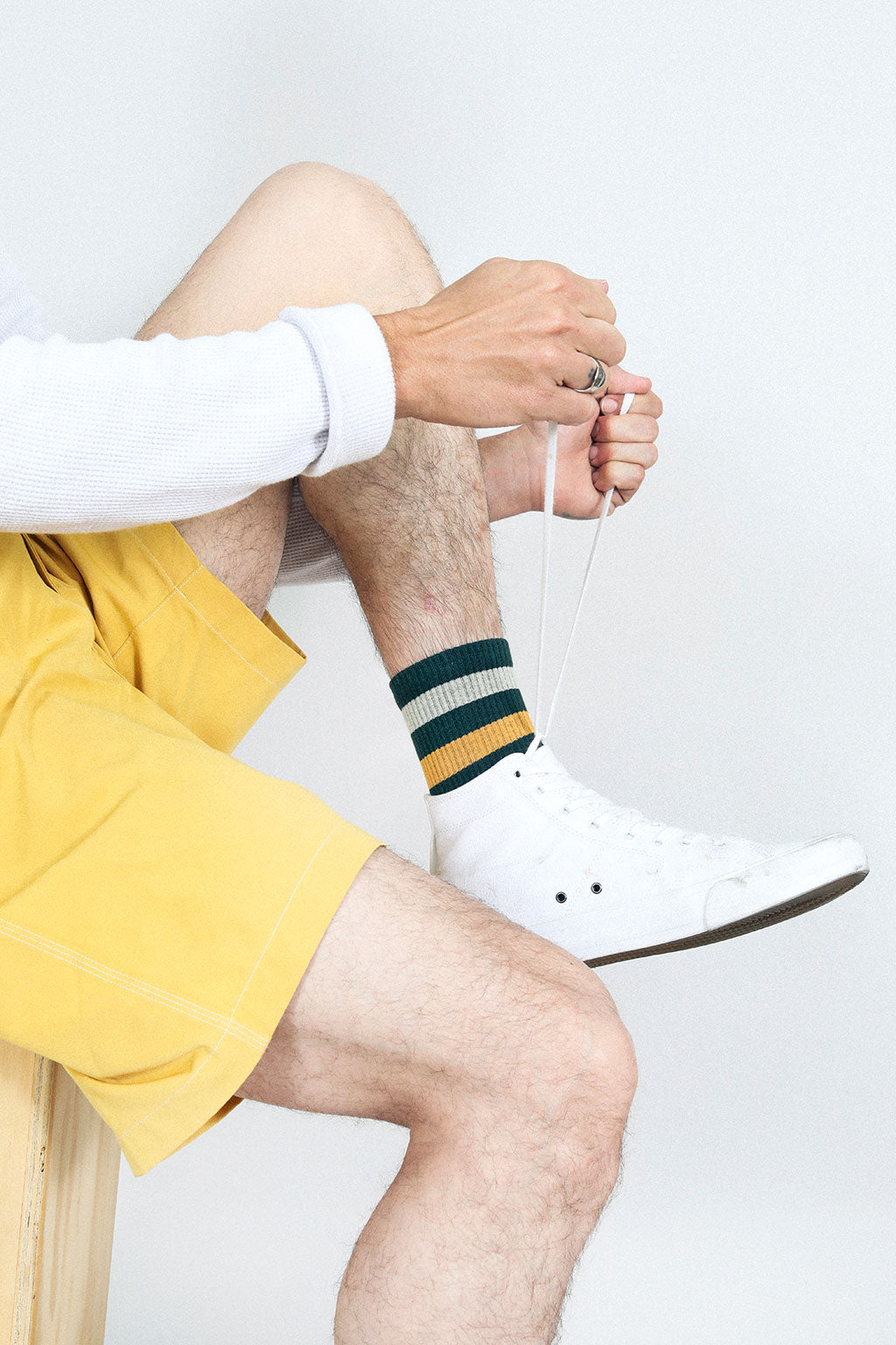 Man tying up shoe wearing Tailored Union green and yellow tube socks